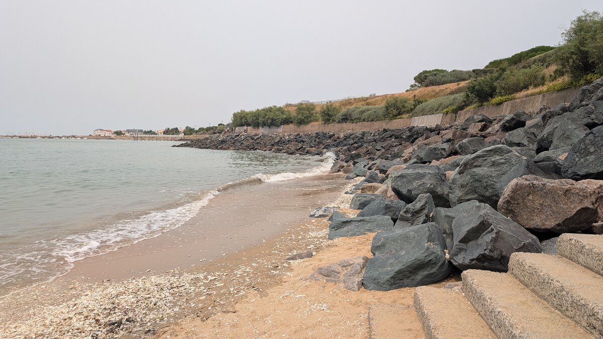 Rivage paisible bordé de rochers et escalier descendant vers la plage