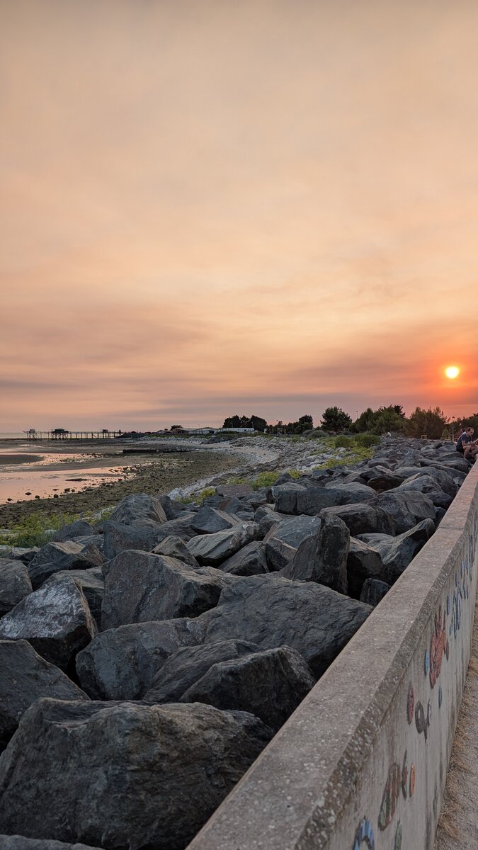 Coucher de soleil orangé sur la mer et les rochers