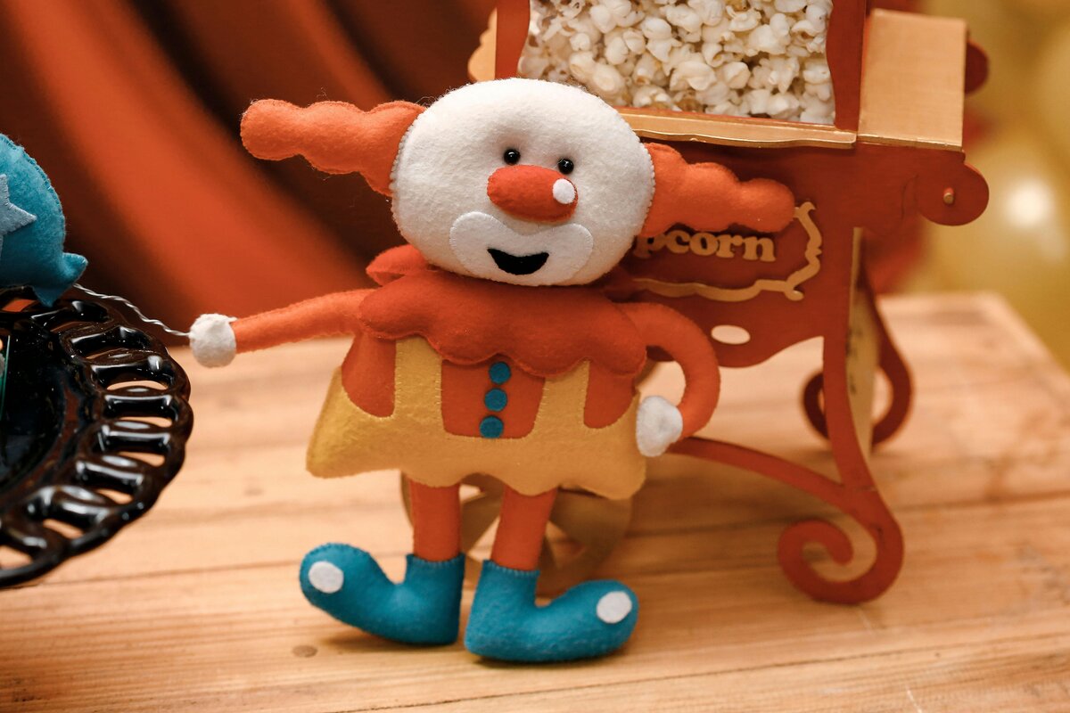 Petite poupée clown en feutrine avec son nez orange et ses chaussures bleues